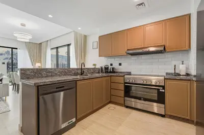 a kitchen with wooden cabinets and stainless steel appliances at Five-Bedroom plus maid's room villa with Multiple En-Suites Sunset Roof Terraces & Exceptional Space in Dubai