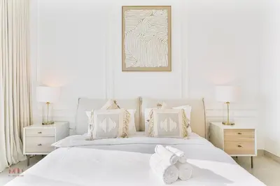 a white bedroom with a white bed with two night stands at Canal-Side Living Elegant 2BR at Canal Front in Dubai