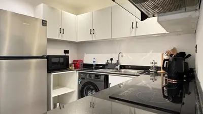 a kitchen with white cabinets and a stainless steel refrigerator at 1BDR Centrally Located Near Metro in Dubai