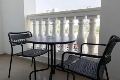 a table and two chairs in front of a balcony at StayShort - Modern JVC 1 bed Sleeps 4 with Swimming Pool in Dubai
