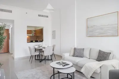a white living room with a couch and a table at StayShort - Modern JVC 1 bed Sleeps 4 with Swimming Pool in Dubai