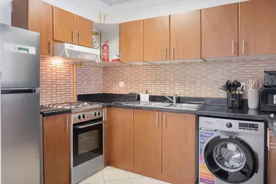 a kitchen with a washing machine and a washer at StayShort - Modern JVC 1 bed Sleeps 4 with Swimming Pool in Dubai