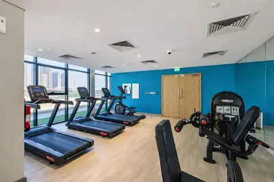a gym with a row of treadmills and exercise bikes at TRPS - Azizi Riviera 5, Al Meydan - Modern Luxury 1BR, Minutes to Burj Khalifa in Dubai