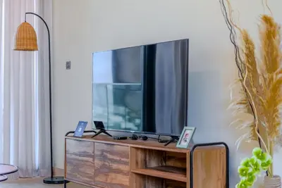 a flat screen tv sitting on top of a wooden entertainment center at TRPS - Azizi Riviera 5, Al Meydan - Modern Luxury 1BR, Minutes to Burj Khalifa in Dubai