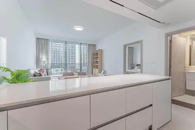 a kitchen with white cabinets and a living room at HAVN - 1 bed in Luma Parks, JVC in Dubai