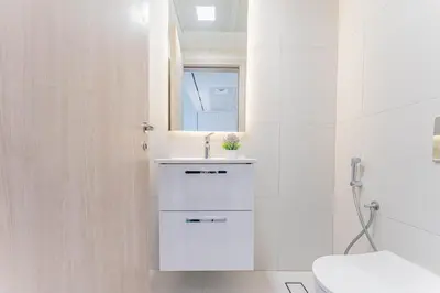 a white bathroom with a sink and a toilet at HAVN - 1 bed in Luma Parks, JVC in Dubai