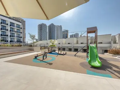 a playground with two swings and a green slide at Boutique Studio at Binghatti Aurora by Czechin in Dubai