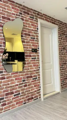 a brick wall with a mirror and a white door at Studio Centrally Located Near to Metro in Dubai