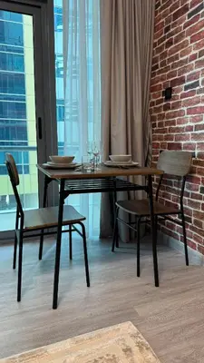 a dining table and chairs in a room with a brick wall at Studio Centrally Located Near to Metro in Dubai