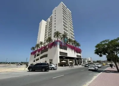 a tall building with palm trees in front of a street at Modern 1BHK Equiti Arcade- Al Furjan -Near Metro in Dubai
