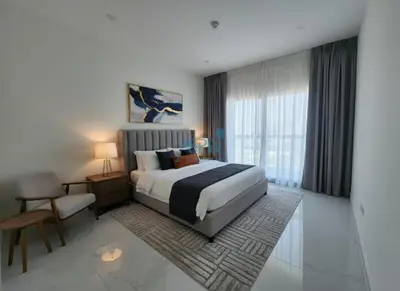 a bedroom with a bed and a table and a chair at Modern 1BHK Equiti Arcade- Al Furjan -Near Metro in Dubai