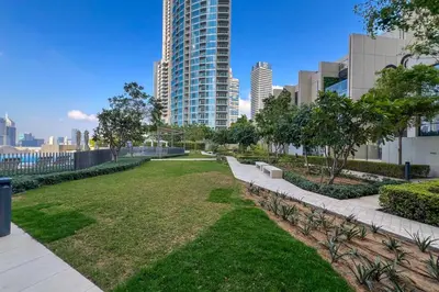 a park in the middle of a city with tall buildings at Waves - Luxury 2BR Apt With Burj Khalifa & Fountain View in Dubai