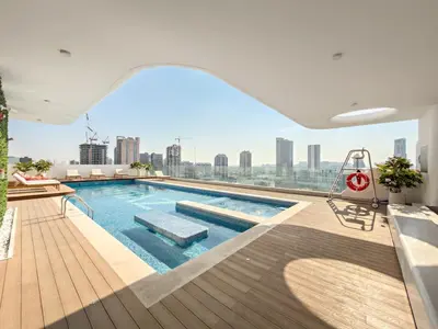 a swimming pool on the roof of a building with a city skyline at VayK - Bright Modern Apartment in JVC - 1BR Gem in Dubai