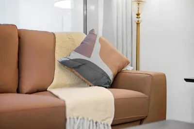 a brown couch with a throw pillow on it at Modern 2BDR Stay-Near Metro-Al Furjan in Dubai