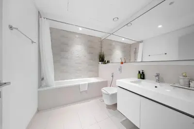 a white bathroom with a tub and a toilet and a sink at VayK - Elegant 2BR at Emaar Beachfront with Beach Access in Dubai