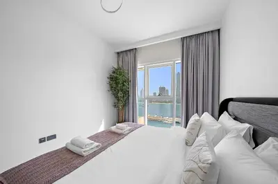 a bedroom with a large bed with a large window at VayK - Elegant 2BR at Emaar Beachfront with Beach Access in Dubai