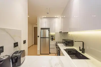 a kitchen with white cabinets and a stainless steel refrigerator at VayK - Chic 1BR Urban Getaway in Dubai