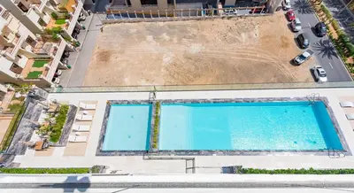 an overhead view of two swimming pools in a building at VayK - Chic 1BR Urban Getaway in Dubai