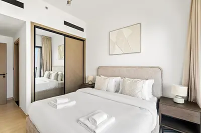 a white bedroom with a large bed and a mirror at VayK - Comfortable 1BR in JVC in Dubai