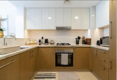 a kitchen with white cabinets and a stove top oven at Luxury Apartments in Downtown Near Dubai Mall and Burj Khalifa View in Dubai