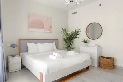 a white bedroom with a white bed with a mirror at VayK - Inviting 1BR in Dubai Marina with Stunning Views in Dubai