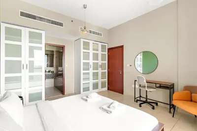 a bedroom with a bed and a desk and a mirror at VayK - Light-Filled and Spacious 1BR in JBR in Dubai