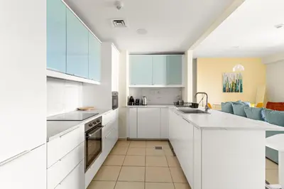 a kitchen with white cabinets and a blue couch at VayK - Light-Filled and Spacious 1BR in JBR in Dubai
