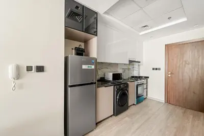 a kitchen with a refrigerator and a washer and dryer at VayK - Chic Studio in Silicon Oasis with Pool View in Dubai