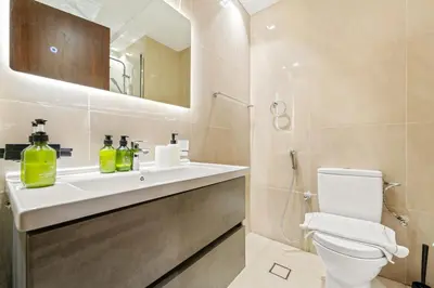 a bathroom with a sink and a toilet and a mirror at VayK - Chic Studio in Silicon Oasis with Pool View in Dubai