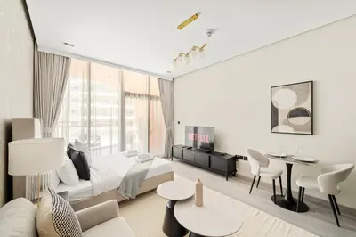 a white bedroom with a bed and a table and chairs at VayK - Chic Studio in Silicon Oasis with Pool View in Dubai
