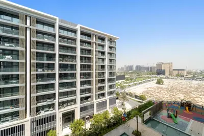an apartment building with a playground in front of a beach at VayK - Refined Studio in Dubai Hills with Pool View in Dubai