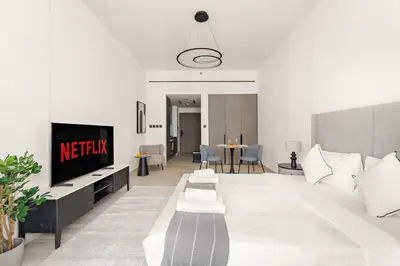 a living room with a large bed and a tv at VayK - Refined Studio in Dubai Hills with Pool View in Dubai