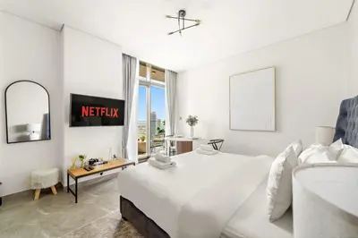 a white bedroom with a white bed and a window at VayK - Sunlit Studio with Canal Views in Business Bay in Dubai