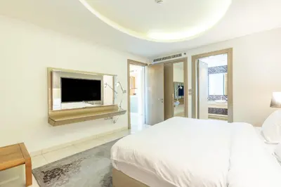 a white bedroom with a bed and a flat screen tv at Superhost - 1BR , Pool & Gym , DAMAC Towers Paramount in Dubai