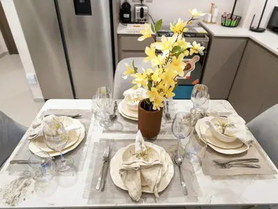 a table with plates and glasses and yellow flowers on it at Prime Downtown Luxury Stays by Burj Khalifa in Dubai