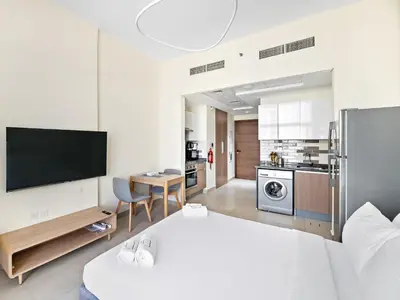 a living room with a bed and a kitchen at Trendy Luxe Studio In Al Furjan close to Metro-17 in Dubai