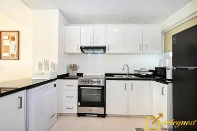 a kitchen with white cabinets and black appliances at Contemporary 3-Bedroom Villa by Deleguest in Dubai