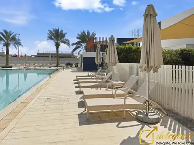 a row of lounge chairs and umbrellas next to a swimming pool at Contemporary 3-Bedroom Villa by Deleguest in Dubai