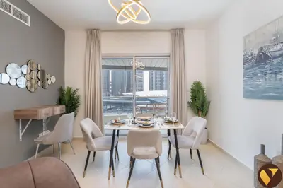 a dining room with a table and chairs and a window at Vogue Marina Diamond Near JBR Beach and Marina Mall, Two Bedroom Apartment with Balcony and City View, Access to all Amenities, Walkable to Sobha Realty Metro Station and Bus Stop in Dubai