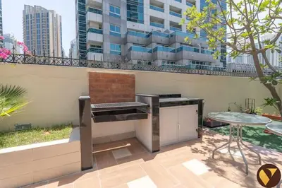 a grill on a patio with a table and a building at Vogue Marina Diamond Near JBR Beach and Marina Mall, Two Bedroom Apartment with Balcony and City View, Access to all Amenities, Walkable to Sobha Realty Metro Station and Bus Stop in Dubai