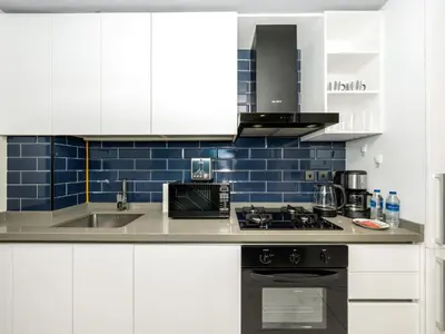 a kitchen with white cabinets and blue tiles at Spacious Studio with Balcony I Near Dubai Mall & Downtown in Dubai