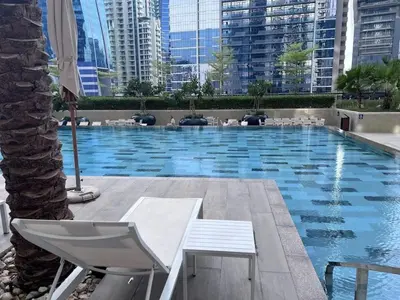 a swimming pool with a chair and an umbrella at Luxurious 1 BDR Zada Tower Business Bay 12 in Dubai