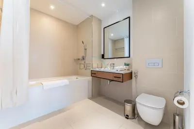 a white bathroom with a toilet and a sink at Prime Location with Direct Mall and Marina Walk Access, Just Outside DMCC Metro Station - VIDA Residences, Dubai Marina by Deluxe Holiday Homes in Dubai