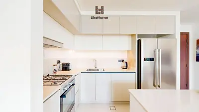 a kitchen with white cabinets and a stainless steel refrigerator at Stunning 2BR Beachfront Living Marina Vista Tower 2 in Dubai