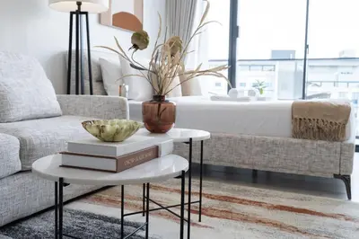 a living room with a couch and a table with books at Chic Pool-View Studio Oxford Gardens by Czechin in Dubai
