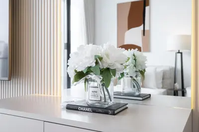 two vases with white flowers sitting on a counter at Chic Pool-View Studio Oxford Gardens by Czechin in Dubai