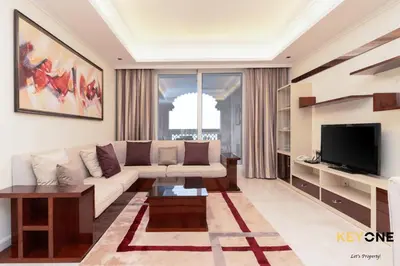 a living room with a couch and a tv at Spacious Beachfront 2BR with Maids Room in Grandeur in Dubai