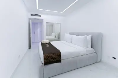 a white bedroom with a bed and a couch at Escape 24 Spacious 1BR Lake View, Global Lake View, JLT in Dubai