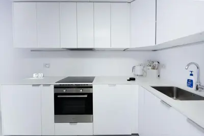 a white kitchen with a stove and a sink at Escape 24 Spacious 1BR Lake View, Global Lake View, JLT in Dubai