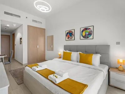 a bedroom with a large white bed with yellow pillows at The Comfort Cove Studio in Azizi Riviera 32 in Dubai